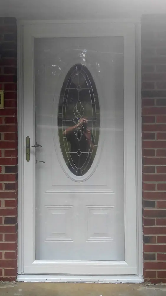 White entry door with an oval glass panel set in brick