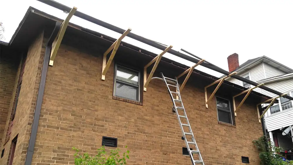 Gutter brackets left on the rafter tails with the gutter down, ladder against the brick
