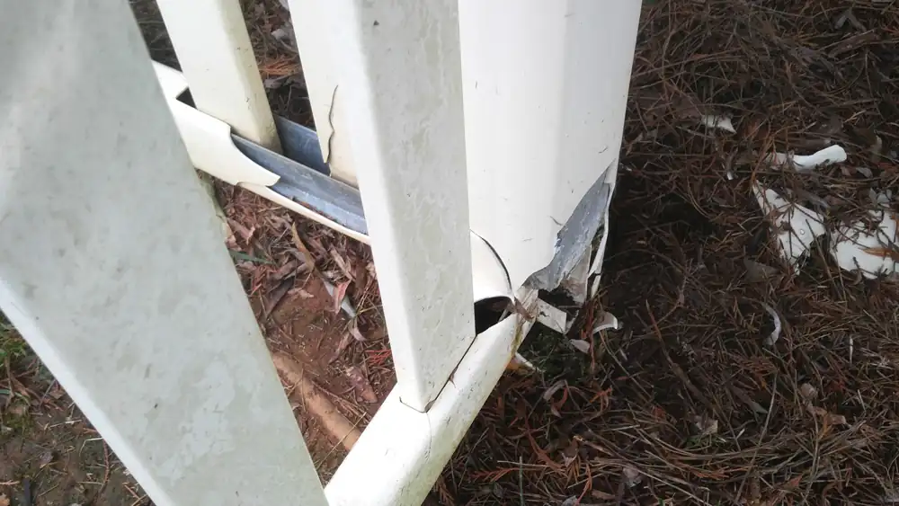 White vinyl fence post split open by a lightning strike