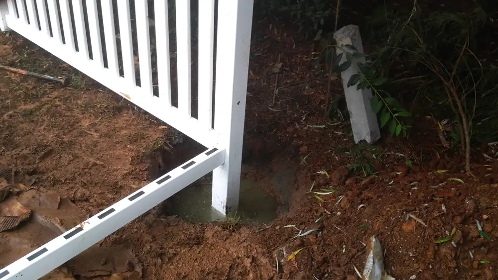 A replacement vinyl post set in a fresh hole along the fence line