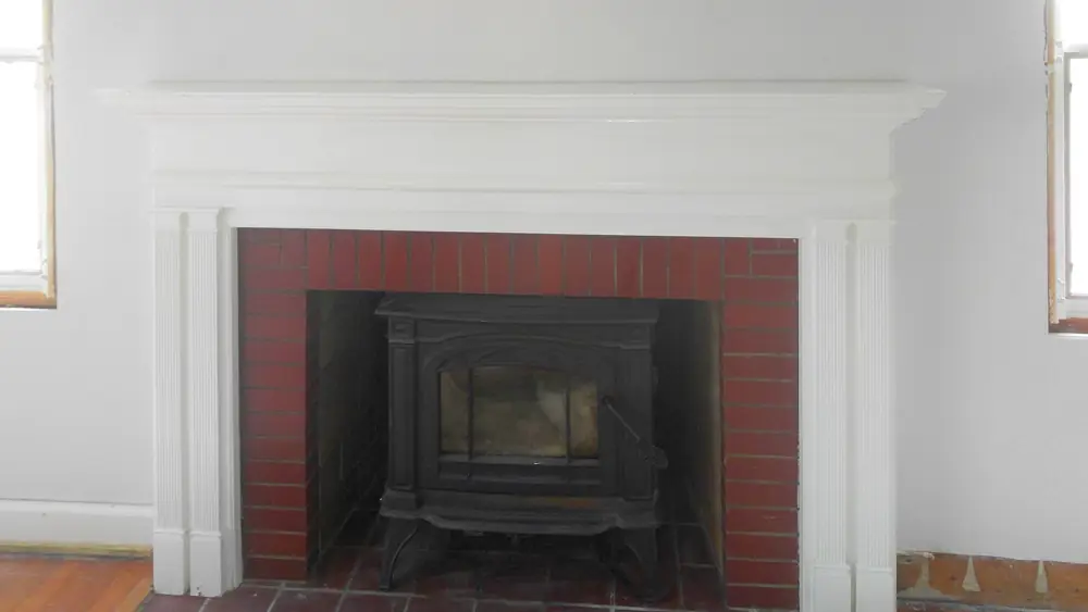 Finished white fireplace wall with the original mantel reinstalled around a cast-iron insert