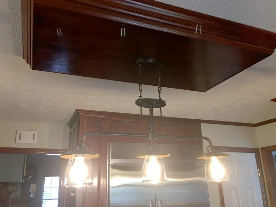 Three Edison-lamp pendants John hung over a kitchen island under a stained wood soffit
