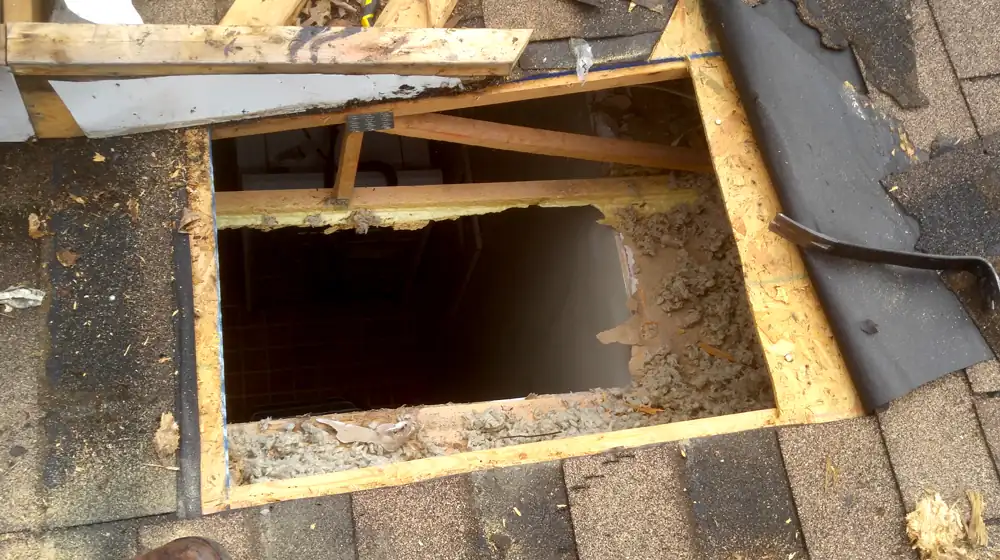 Rotted decking cut open over a laundry room after a long-running leak was traced